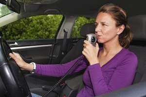 Woman in car blowing into breathalyzer