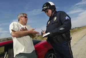 Man having discussion with police officer by car