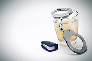 Car key with glass of whiskey and handcuffs