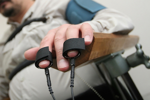 Placing equipment for interrogation of a man with lie detector. Electrodes attached to fingers